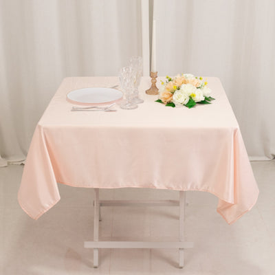 Elegant pink tablecloth on a dining table with floral arrangement and tableware.