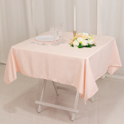 Peach tablecloth draped over a table set with flowers and glassware.