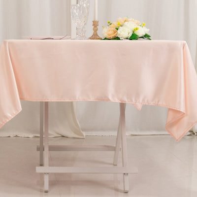Pink tablecloth draped over a table with floral arrangement and decor.