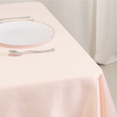 Pink tablecloth draped elegantly with a white plate and silverware on a table.