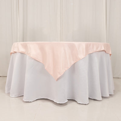 Round table with white tablecloth and pink satin overlay
