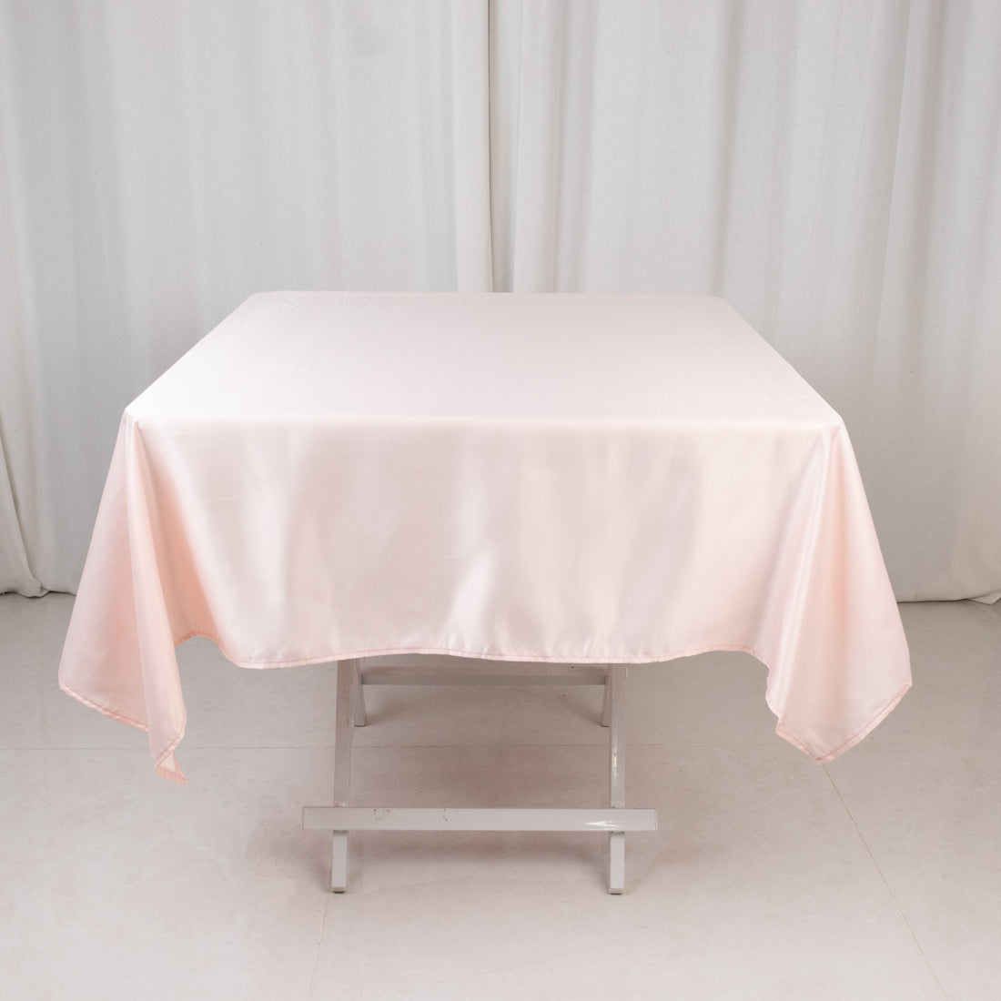 Pink satin tablecloth draped over a table in a studio setting