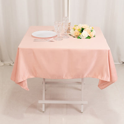 Pink tablecloth draped over a table set for dining with plates and flowers.