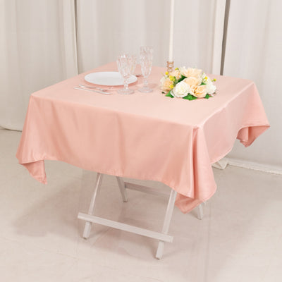 Pink tablecloth draped over a folding table with plates and a floral centerpiece.