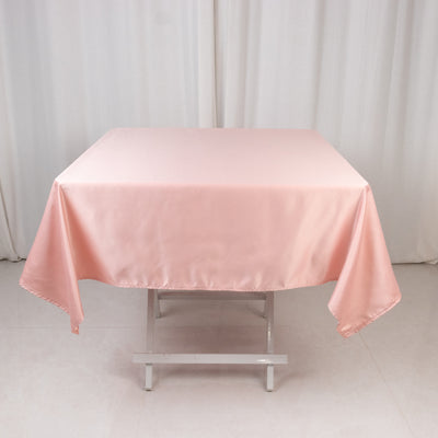 Pink satin tablecloth on a folding table in a studio setting.