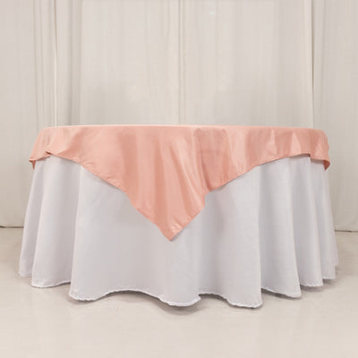 Round table with white tablecloth and pink satin overlay