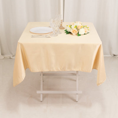 Elegant cream tablecloth on a dining table with flowers and dinnerware.