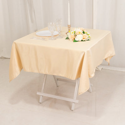 Beige tablecloth draped over a table set with plates, glasses, and flowers.