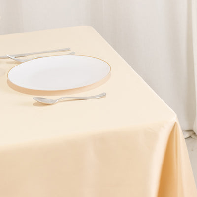 Elegant white plate with gold rim on a soft beige tablecloth.
