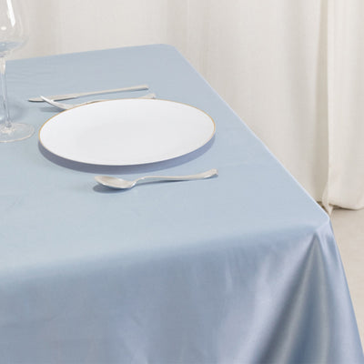 Elegant blue tablecloth with a white plate and cutlery set on a dining table.