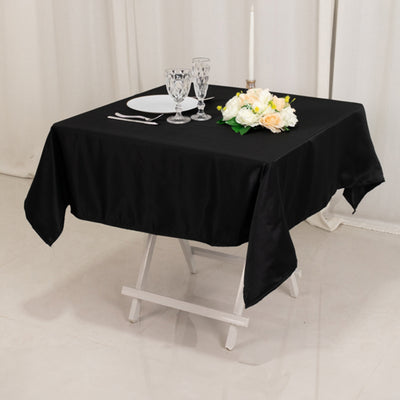 Elegant black tablecloth draped on a table with floral centerpiece and glassware.