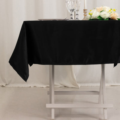Black tablecloth draped elegantly over a white table with decorative flowers.