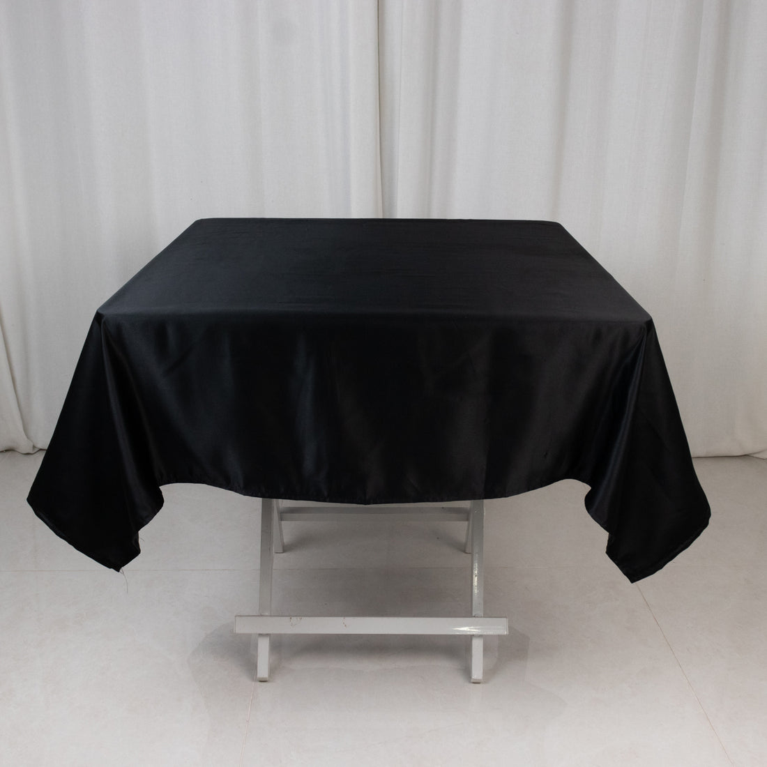Black satin tablecloth on a folding table in a studio setting.