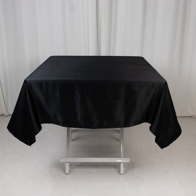 Black satin tablecloth on a folding table in a studio setting.