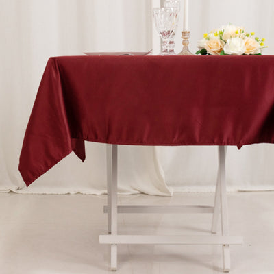 Burgundy tablecloth draped elegantly over a white table with floral centerpiece.