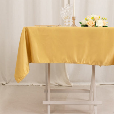 Yellow tablecloth draped on a table with floral centerpiece and glassware.