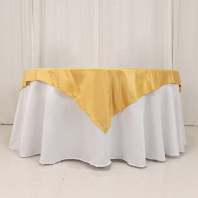 Round table with white tablecloth and gold satin overlay