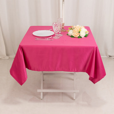 Pink tablecloth draped over a table set with dishes and flowers.