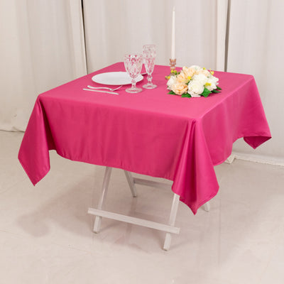 Pink tablecloth draped over a table set with plates, glasses, and flowers.