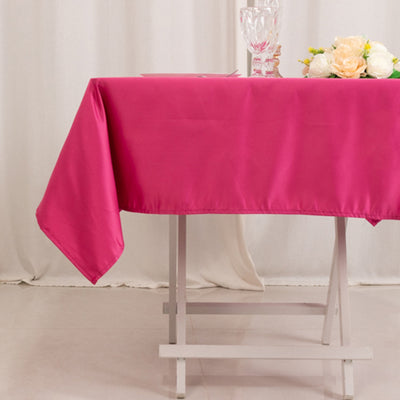 Pink tablecloth draped over a white table with flowers and glassware