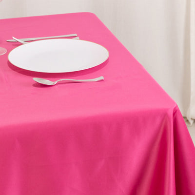 Pink tablecloth with a white plate and silver cutlery on a dining table.