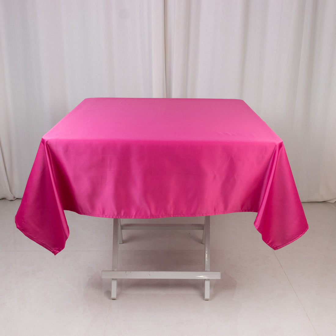 Pink satin tablecloth on a white table against a neutral background.