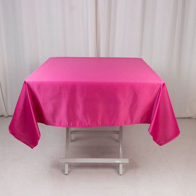 Pink satin tablecloth on a white table against a neutral background.