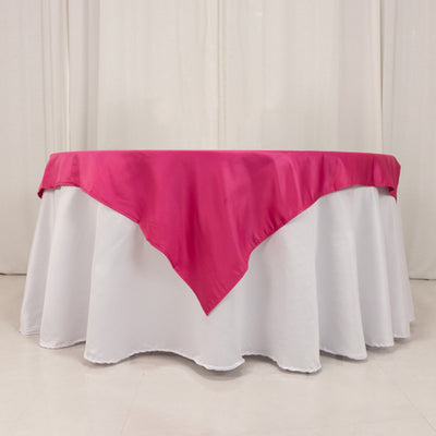 Round table with a white tablecloth and a pink satin overlay.