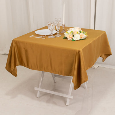 Elegant gold tablecloth draped over a table set for dinner with flowers and glassware.