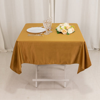Elegant gold tablecloth draped over a dining table with floral centerpiece and dinnerware.