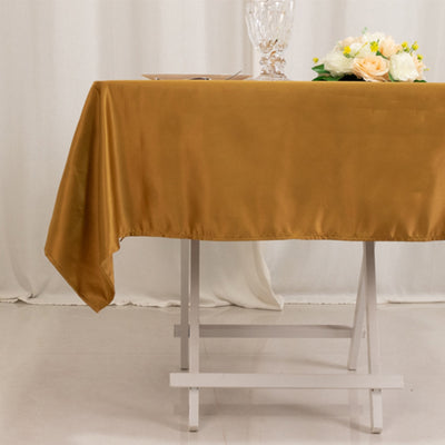 Brown satin tablecloth draping over a white table with flowers and glassware.