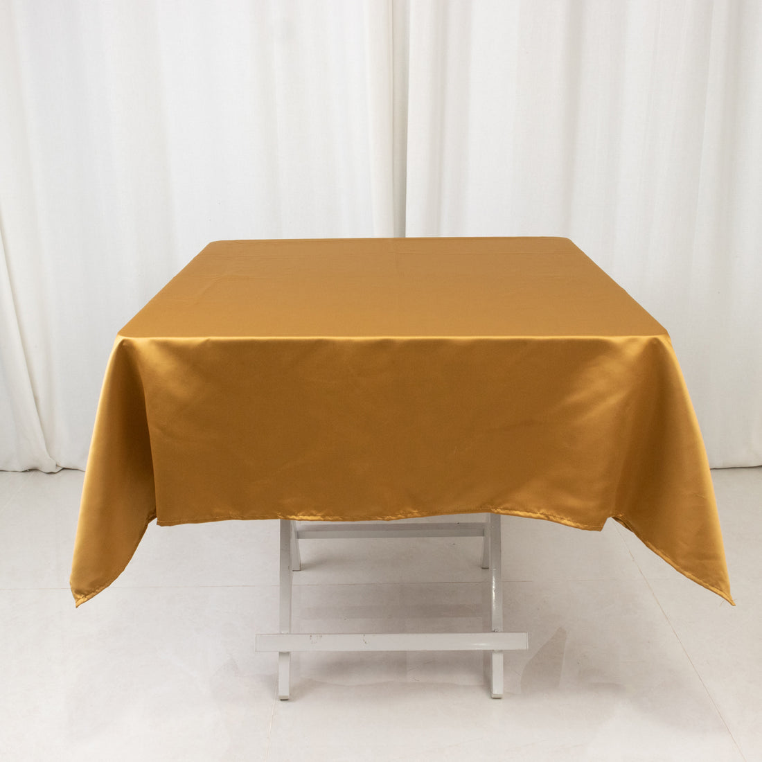 Gold satin tablecloth draped over a white folding table