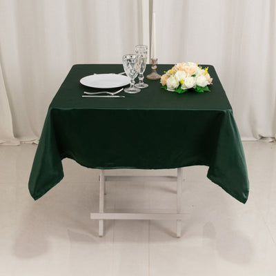 Green tablecloth draped over a table set with glassware and flowers.