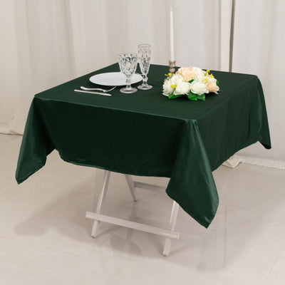 Green tablecloth on a dining table set with plates and floral centerpiece.