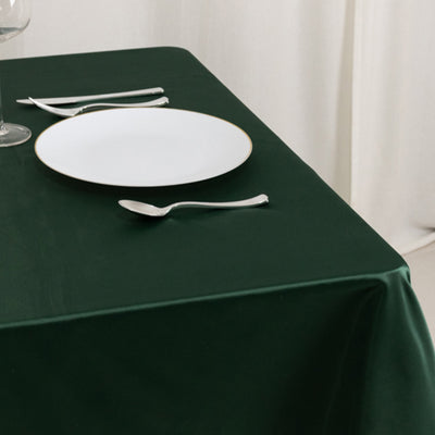 Elegant green tablecloth with white plate and silverware.