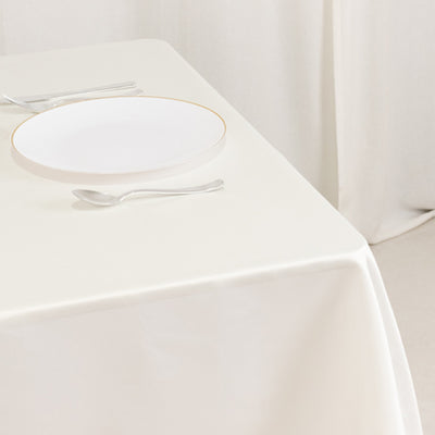 Elegant white plate with gold rim on a cream tablecloth.
