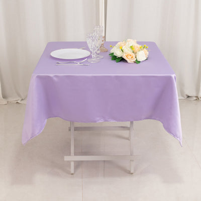 Purple tablecloth on a dining table with plate and floral arrangement.