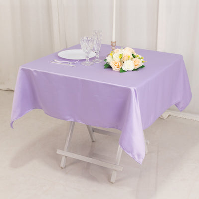 Purple satin tablecloth draped over a table with flowers and glassware.