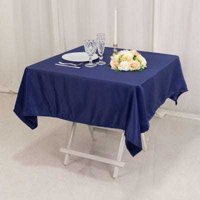 Navy blue tablecloth on a folding table with plates, glasses, and a floral centerpiece.