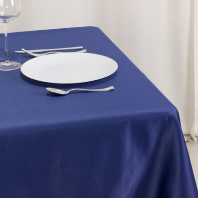 Navy blue tablecloth draped over a table with dining utensils and a plate.