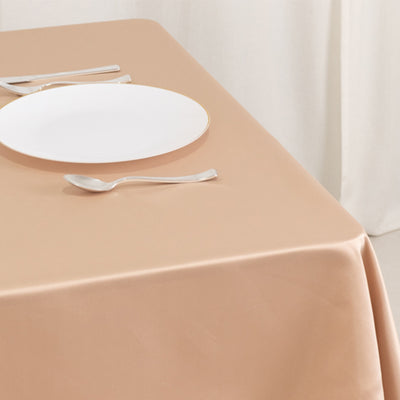 Elegant beige tablecloth with a white plate and silver utensils.