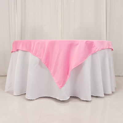 Pink tablecloth draped over a white table in a studio setting.