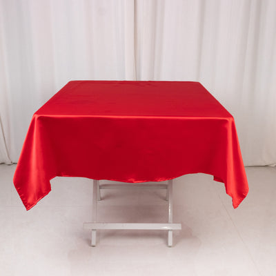 Red satin tablecloth on a folding table with a plain background.