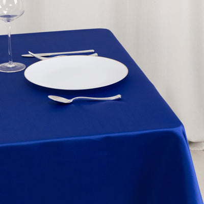 Elegant blue tablecloth with a white plate and cutlery set on a dining table.