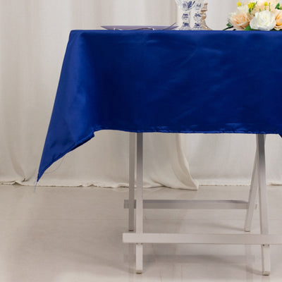Blue satin tablecloth draped over a white table in a decorated setting.