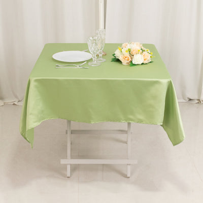 Green tablecloth on a dining table with plate, glassware, and floral centerpiece.