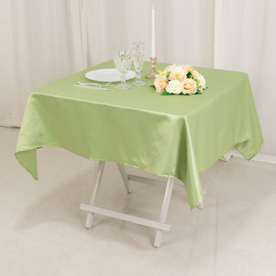 Green satin tablecloth with a floral centerpiece and dining setup.