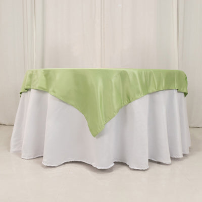 Green satin table cover draped over a round table.