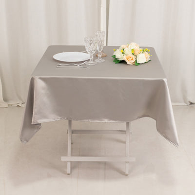 Elegant gray tablecloth with dinnerware and floral arrangement on a dining table.