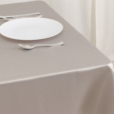 Elegant table setting with a white plate and silver utensils on a beige tablecloth.